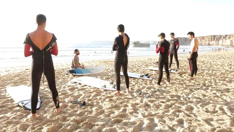 Grupo de la RUT con neoprenos en la playa durante una salida de surf